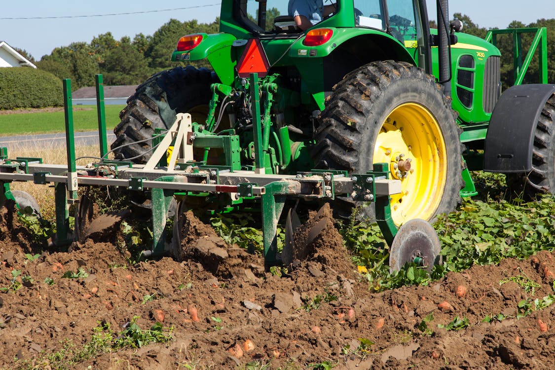 Tractor moderno trabajando en explotación agrícola visto en detalle desde campo arado