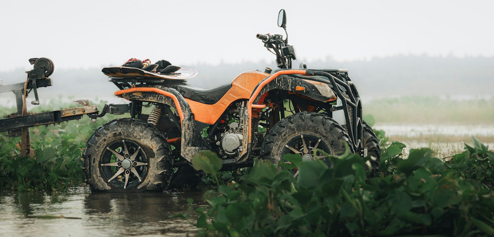 Quad ATV utilitario de uso agrícola aparcado en camino rural junto a una finca